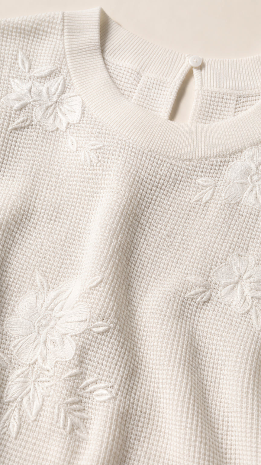Close-up of textured knit fabric and floral embroidery detail