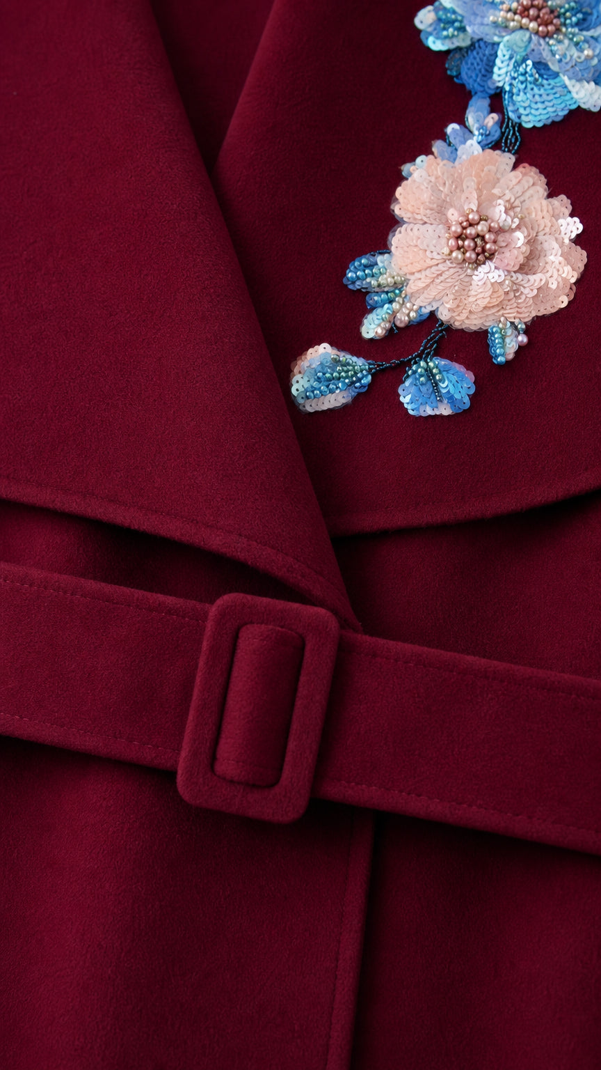 Close up of collar embroidery and belt buckle on Burgundy coat