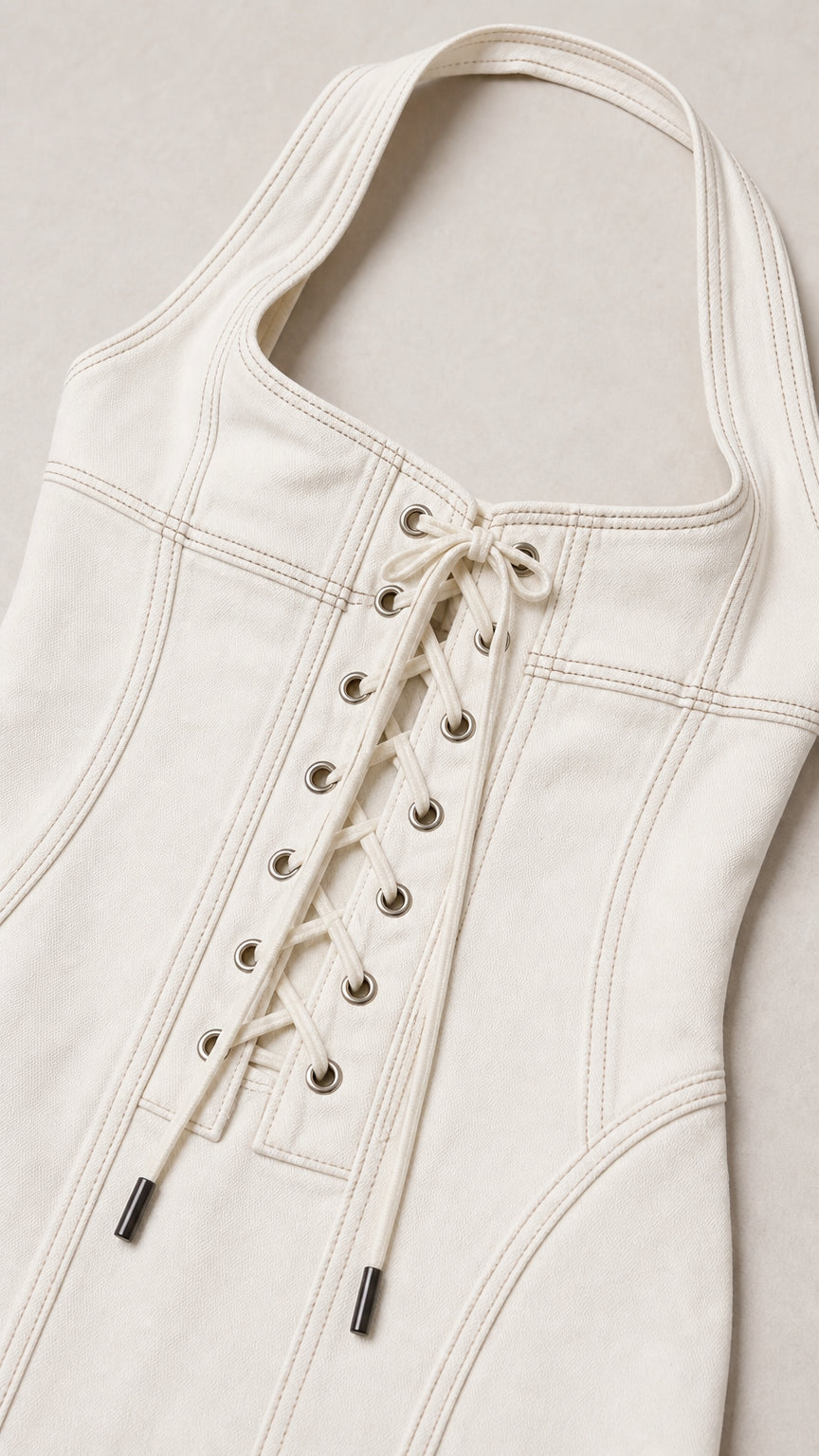 Close-up detail of halter neckline, contrast stitching, and lace-up grommets