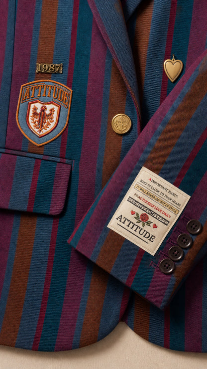Close-up detail of embroidered crest patch, metallic button, and striped suiting fabric