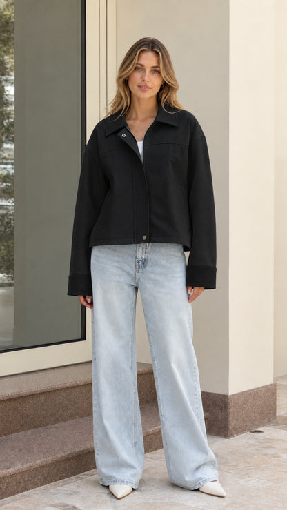 Model wearing black cropped zip-up jacket with light wash wide-leg denim