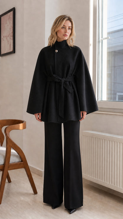 Black high-neck belted cape coat styled with black wide-leg trousers