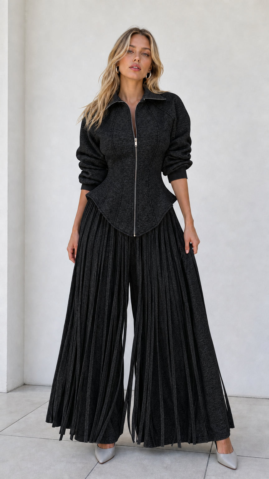 Model wearing black zip-up corset top and matching black pleated wide-leg trousers
