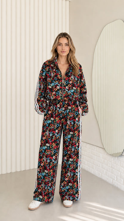Woman wearing black floral print zip-up tracksuit two-piece set