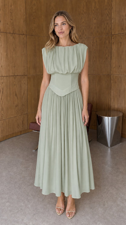 Full-length front view of sage green sleeveless basque waist pleated midi dress