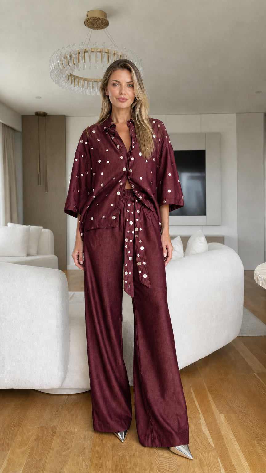 Model wearing burgundy polka dot button-up shirt and wide-leg trousers set