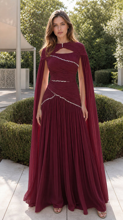Front view of rich burgundy pleated evening gown with cape and crystal embellishments