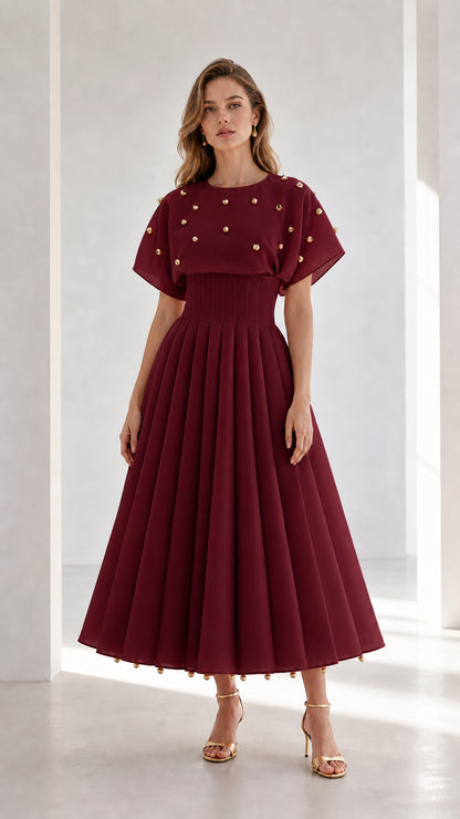 Front view of model wearing burgundy wine red studded pleated midi dress with flutter sleeves