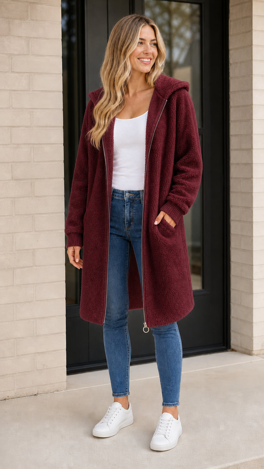 Front view of woman wearing burgundy long faux shearling hooded coat