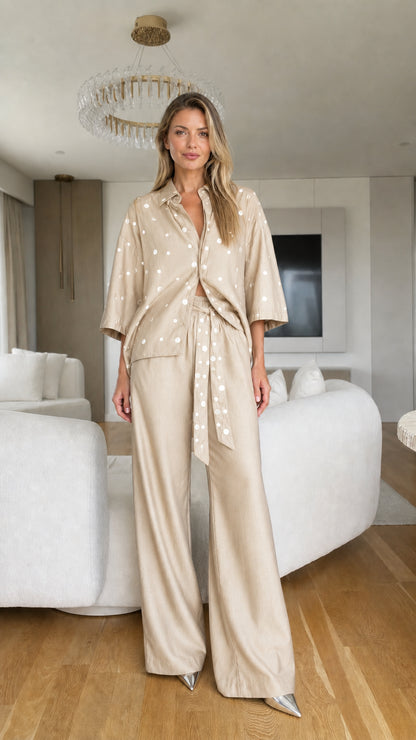 Model wearing beige champagne polka dot collared shirt and wide-leg trousers set