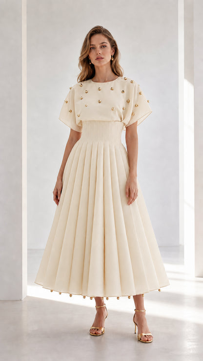 Front view of model wearing champagne cream studded pleated midi dress with flutter sleeves